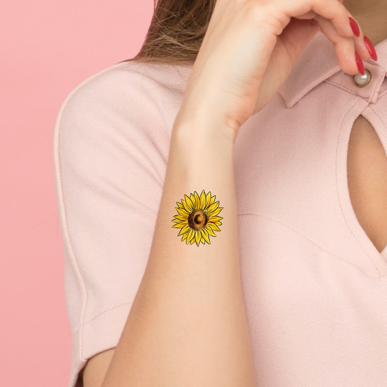 May include: A temporary tattoo of a yellow sunflower with a brown center.