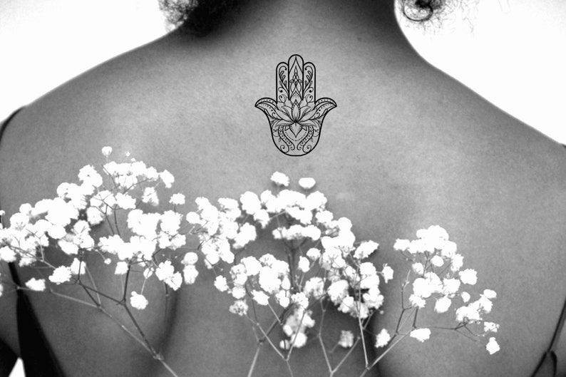 May include: A black and white hamsa hand tattoo design with intricate details.