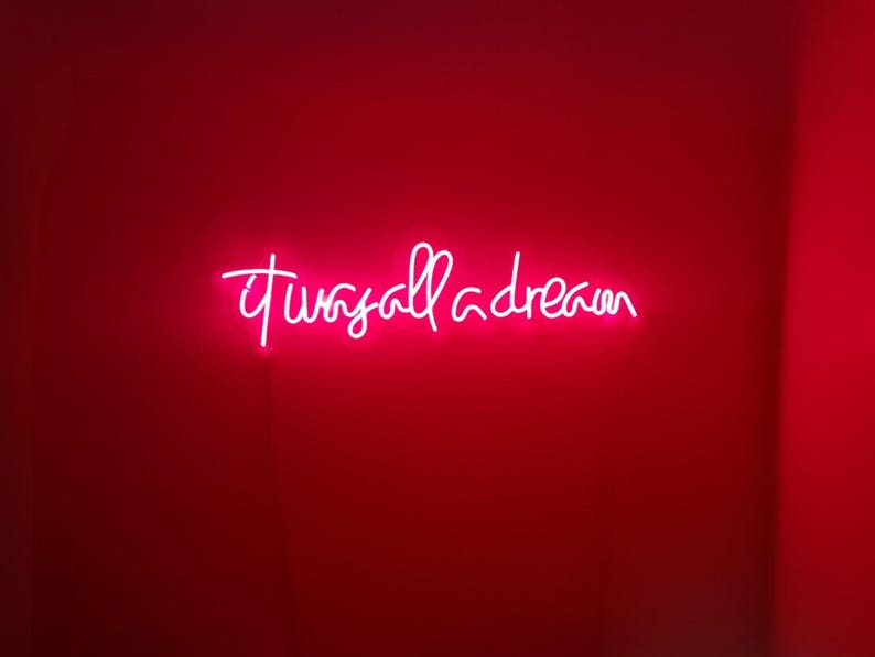 Puede incluir: Un letrero de ne&oacute;n en una pared roja que dice "it was all a dream".