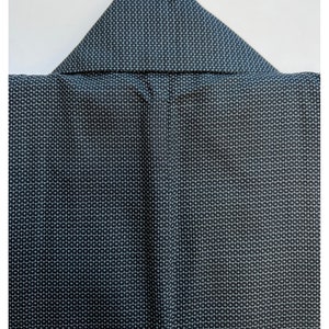 May include: A black kimono with a white geometric pattern. The kimono is folded and has a collar.