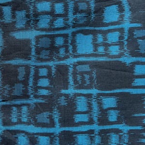 May include: Close-up of a textile with a repeating pattern of dark blue rectangular shapes against a bright teal background. The fabric has a slightly textured appearance, with the dark blue shapes appearing somewhat blurred.