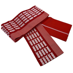Puede incluir: Tela roja con patrones de flechas blancas y un borde a rayas. La tela está doblada y dispuesta para mostrar el diseño. El material parece estar tejido, con una textura suave. El diseño general es simétrico.