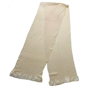 May include: A cream-colored knitted scarf with a ruffled edge.