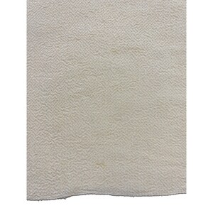 May include: A close-up of a cream-colored fabric with a textured surface.