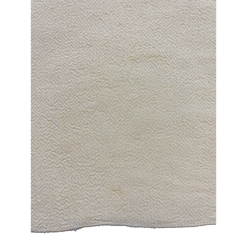 May include: A close-up of a cream-colored fabric with a textured surface.