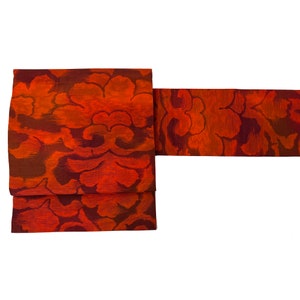 May include: A red and brown fabric with a floral pattern. The fabric is folded in half and the ends are visible.