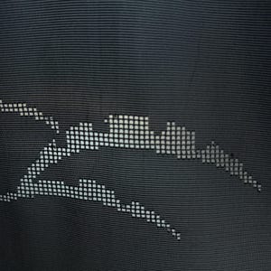 Puede incluir: Primer plano de una tela gris oscuro con un diseño pixelado blanco. El diseño parece ser una representación estilizada del horizonte de una ciudad y un rayo. La tela tiene una textura acanalada.