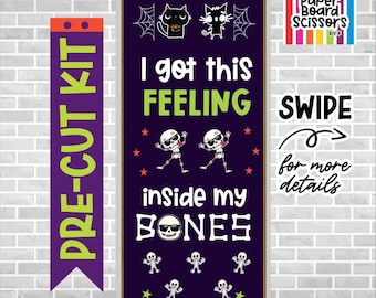 Op de afbeelding: Een verticale paarse deurdecoratieset met de tekst I got this FEELING inside my BONES. Het ontwerp bevat twee zwarte katten, spinnenwebben, dansende skeletten met zonnebrillen en kleine sterren. De banner is gelabeld als PRE-CUT KIT.