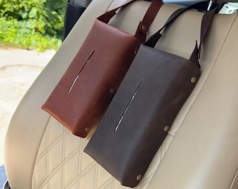 May include: Two leather tissue box holders with straps to hang on a car headrest. One is brown and the other is dark brown.