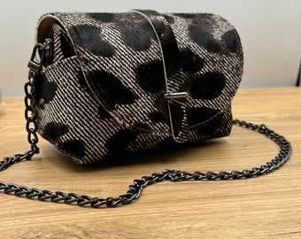 May include: A small black and white leopard print crossbody bag with a silver buckle and a black chain strap.