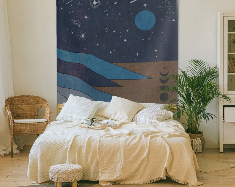 May include: A tapestry featuring a night sky with stars, a crescent moon, and a large blue planet. The bottom of the tapestry depicts a landscape of blue and brown hills.