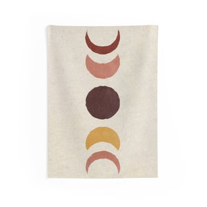 May include: A tapestry with a minimalist design featuring five moon phases in shades of brown, pink, and yellow on a beige background.