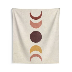 May include: A tapestry featuring a vertical arrangement of five moons in various phases. The moons are painted in shades of brown, orange, and pink against a beige background.