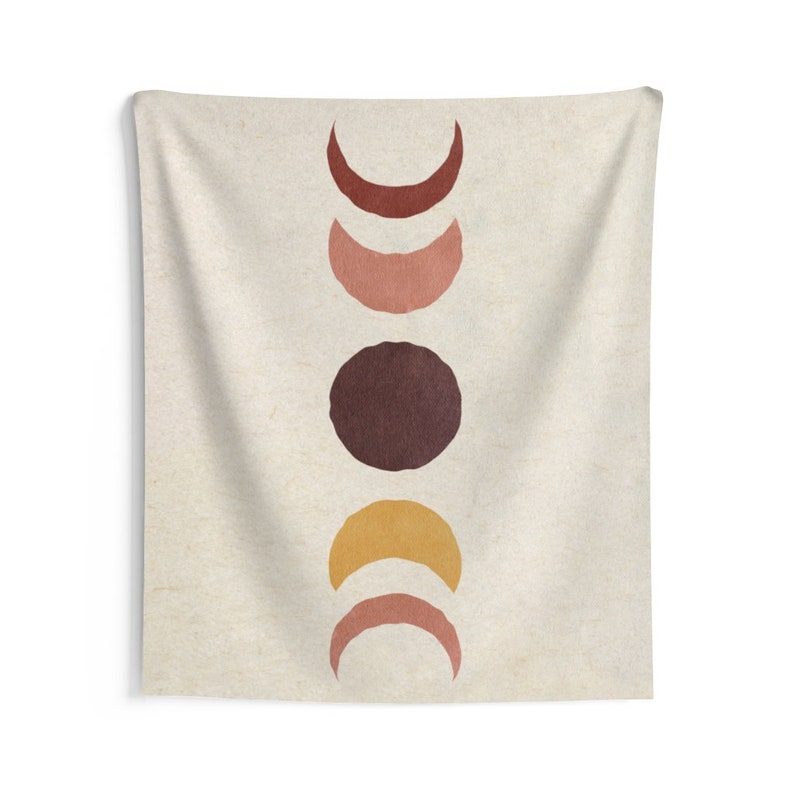 May include: A tapestry featuring a vertical arrangement of five moons in various phases. The moons are painted in shades of brown, orange, and pink against a beige background.