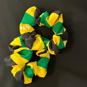 May include: Two yellow, green, and black striped scrunchies. The scrunchies are made of fabric and are tied together.