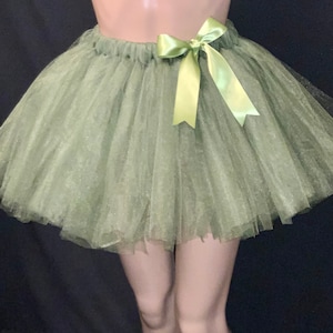 Może przedstawiać: Jasnozielona spódnica tutu wykonana z warstw tiulu. Spódnica ma marszczoną talię i jest ozdobiona jasnozieloną satynową kokardą. Przeznaczona do tańca lub kostiumów.