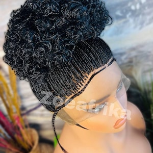 May include: A black braided wig with a high bun. The wig is made with small braids and has a lace front.