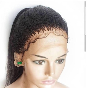 May include: A black braided wig with a lace front. The wig is styled in a ponytail and has a natural-looking hairline.