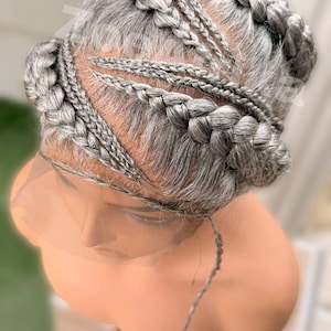 May include: A gray braided wig styled on a mannequin head. The wig features multiple braids of varying sizes, arranged in a pattern across the top and sides. The wig is designed to be worn and is attached to a lace front.