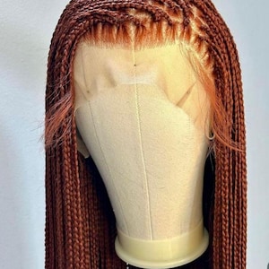 Könnte beinhalten: Eine braune geflochtene Perücke mit einem Spitzenfront. Die Perücke befindet sich auf einem Mannequin-Kopf.