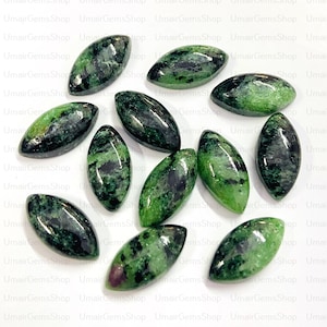 Puede incluir: Una colección de 12 piedras preciosas ovaladas de color verde y negro. Las piedras preciosas son lisas y pulidas, con una variedad de patrones y texturas.