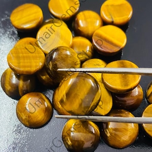 May include: A collection of round, polished tiger's eye cabochons in various shades of golden brown. The stones have a chatoyant effect, with a shimmering, iridescent sheen.