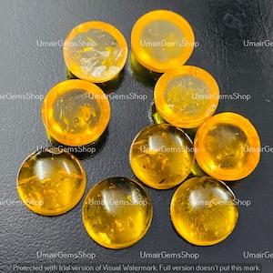 Puede incluir: Diez cabujones redondos de ámbar naranja con un aspecto translúcido y nublado. Los cabujones tienen un diámetro de aproximadamente 2,5 cm.