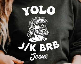 May include: Black sweatshirt with a white graphic of Jesus wearing sunglasses and a crown of thorns. The text "YOLO J/K BRB Jesus" is printed on the sweatshirt.