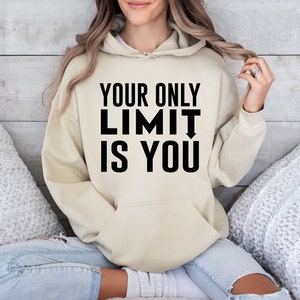 Könnte beinhalten: Ein beiger Hoodie mit dem Text "YOUR ONLY LIMIT IS YOU" in Schwarz auf der Vorderseite.