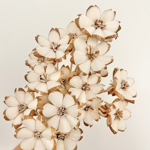 以下が含まれることがあります： 白と茶色の木製の造花の花束。花は繊細で複雑なデザインで、どんな空間にも自然な美しさを添えるのに最適です。