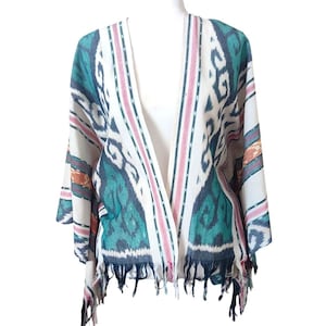 May include: A white, teal, and pink patterned kimono with fringe trim. The open-front garment features a geometric design with teal and white ikat-style patterns, accented by pink and orange stripes. The sleeves are three-quarter length.