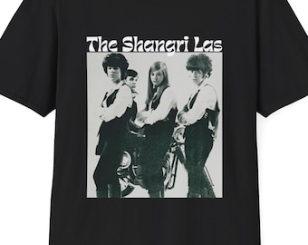 Può includere: Maglietta nera con una grafica bianca di una band chiamata "The Shangri Las". La grafica presenta una foto in bianco e nero dei membri della band.
