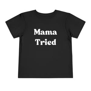 May include: Black short-sleeved t-shirt with white text that reads "Mama Tried".