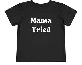 Può includere: Maglietta nera a maniche corte con testo bianco che dice "Mama Tried".