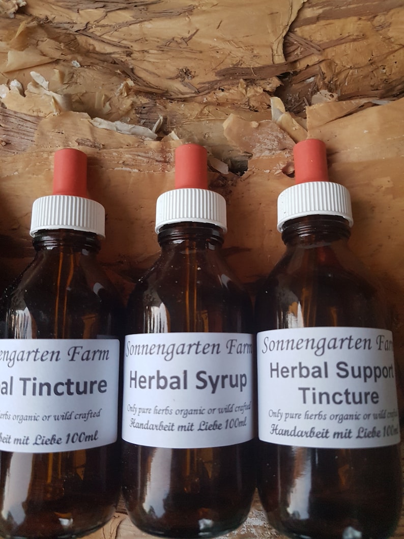 May include: Three glass bottles with dropper tops filled with brown liquid. The bottles are labelled "Sonnengarten Farm Herbal Syrup", "Sonnengarten Farm Herbal Support Tincture", and "Engarten Farm Herbal Tincture". Each bottle has a white label with black text and is 100 ml.