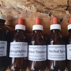 May include: Five amber glass bottles with dropper tops filled with herbal tinctures and syrups. The bottles are labelled with the text "Sonnengarten Farm" and the names of the products, including "Herbal Tincture", "Andrographis", and "Herbal Syrup".