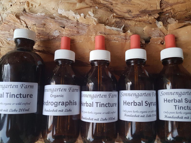 May include: Five amber glass bottles with dropper tops filled with herbal tinctures and syrups. The bottles are labelled with the text "Sonnengarten Farm" and the names of the products, including "Herbal Tincture", "Andrographis", and "Herbal Syrup".