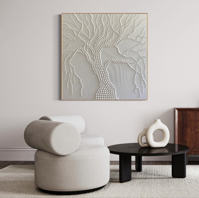 May include: A white, textured, abstract painting of a tree with a gold frame. The tree is made up of small, round shapes that are raised from the surface of the canvas.