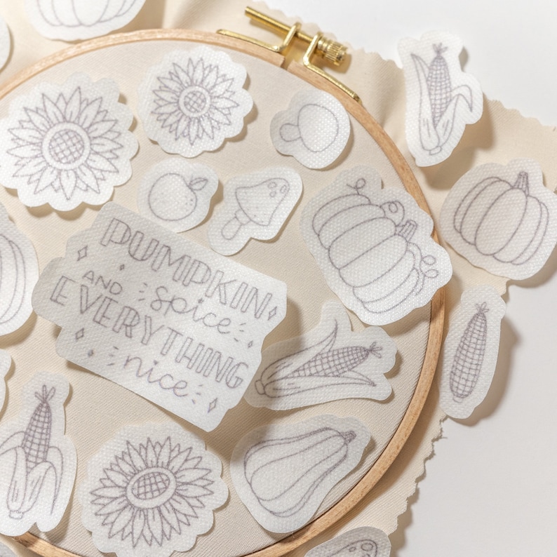May include: A set of iron-on patches featuring various fall-themed designs, including pumpkins, sunflowers, corn, mushrooms, and a quote that reads "Pumpkin Spice and Everything Nice".