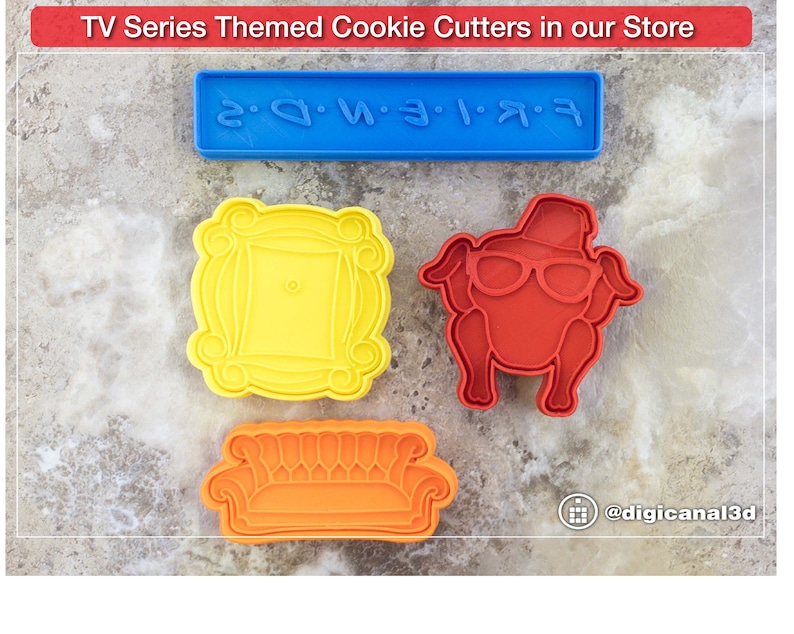 Puede incluir: Cuatro cortadores de galletas en forma de sof&aacute;, marco de fotos, pavo y un letrero que dice "FRIENDS" en pl&aacute;stico azul. Los cortadores de galletas est&aacute;n sobre una superficie gris texturizada.