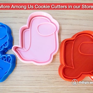 Puede incluir: Tres cortadores de galletas con forma de personajes del videojuego Among Us. Los cortadores son de color rosa, rojo y azul. El cortador rosa tiene forma de tripulante, el cortador rojo tiene forma de tripulante con visera y el cortador azul tiene forma de tripulante con casco.