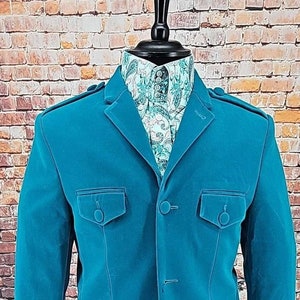 May include: A teal blue velvet blazer with four buttons and two flap pockets. The blazer is on a mannequin with a patterned shirt underneath.