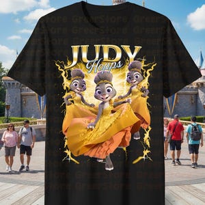 May include: Black t-shirt featuring a graphic of Judy Hopps from Zootopia in a yellow dress. The text "JUDY Hopps" is displayed above the character. The design includes a yellow lightning bolt effect.