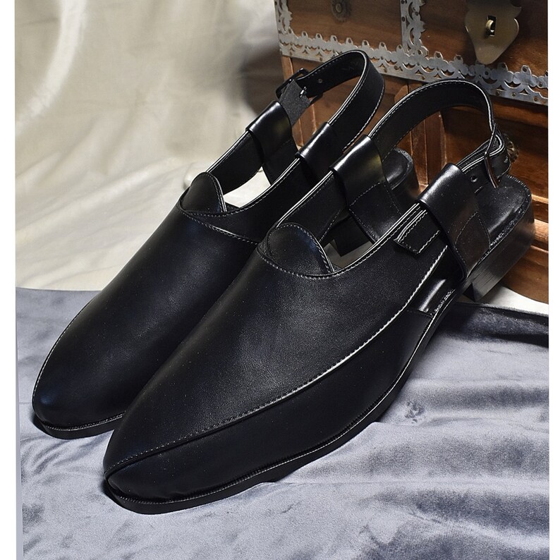 May include: A pair of black leather sandals with a pointed toe and an ankle strap. The sandals have a cut-out design on the top and a buckle closure.