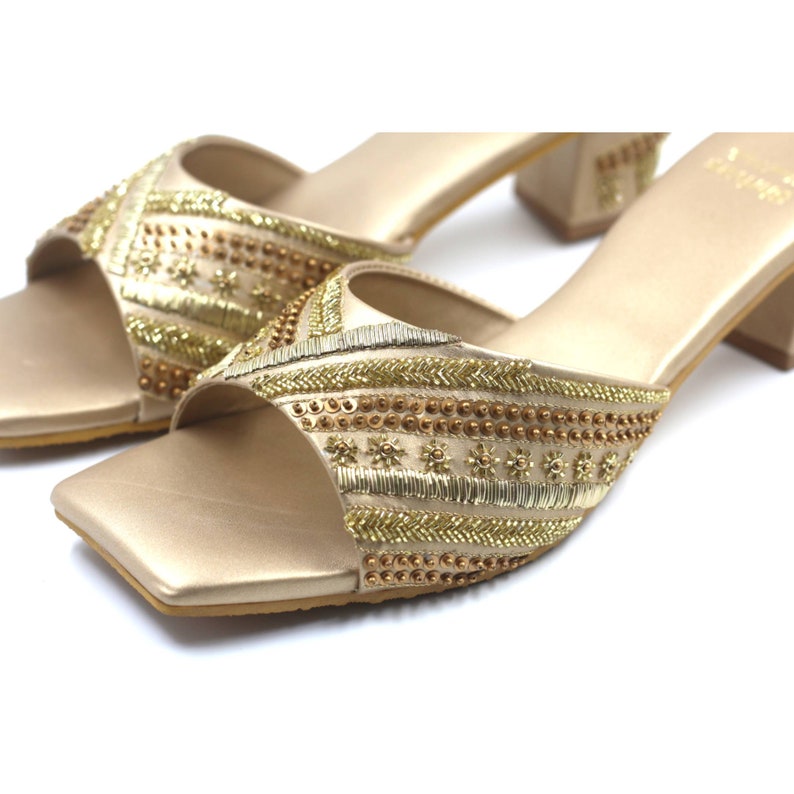 May include: Gold heeled sandals with a square toe and intricate beaded embellishments.