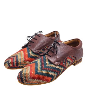 Puede incluir: Un par de zapatos marrones de cuero con cordones y un patr&oacute;n geom&eacute;trico colorido en la punta.