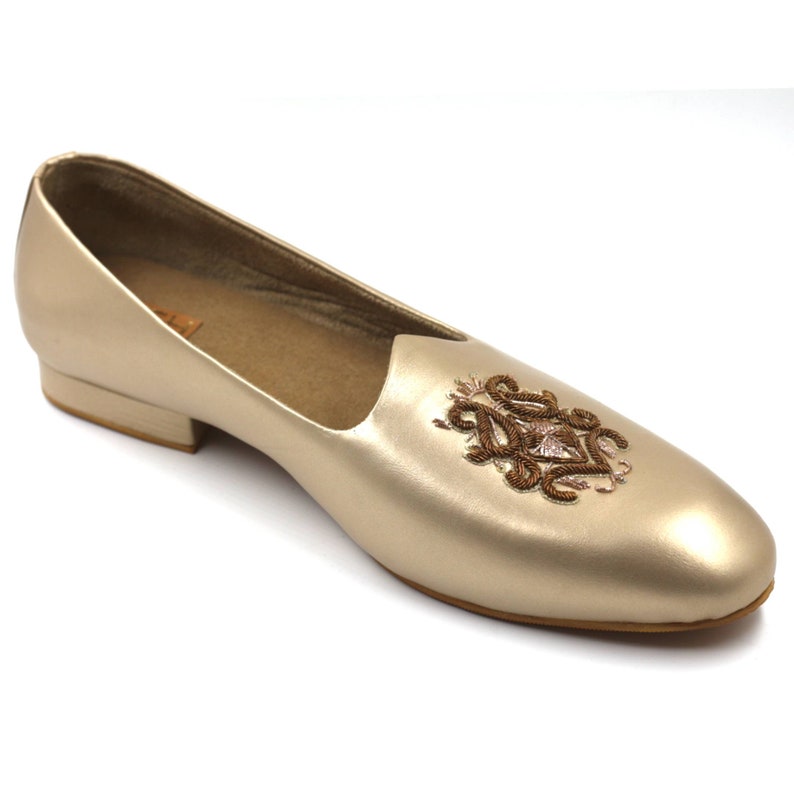 May include: Gold leather slipper with a brown embroidered design on the top.