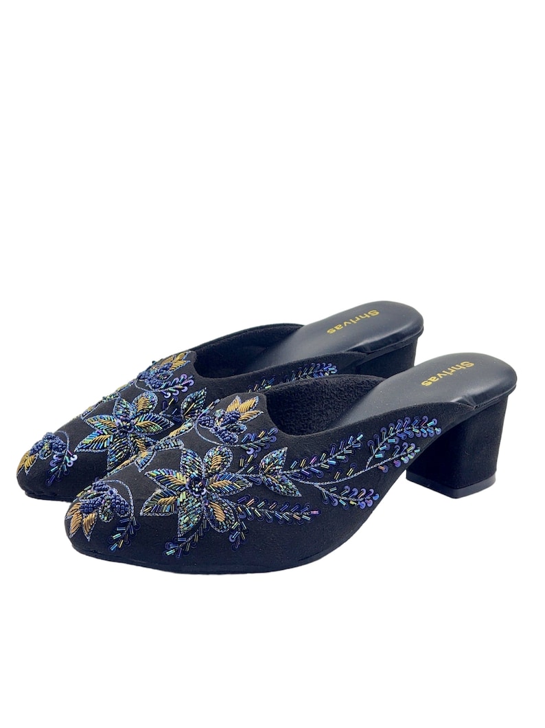 May include: A pair of black heeled mules with floral embroidery. The embroidery features iridescent blue and gold beads.
