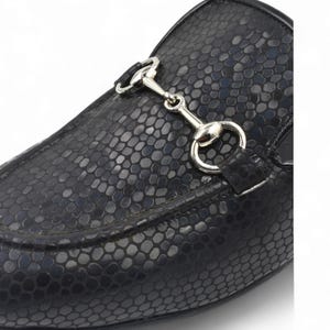 Puede incluir: Zapatos de vestir negros de cuero con estampado de piel de serpiente y detalle de bocado de caballo plateado.