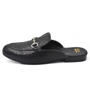 Puede incluir: Mule de cuero negro con estampado de piel de serpiente y hebilla de metal plateado. El zapato tiene un tac&oacute;n peque&ntilde;o y una punta puntiaguda.